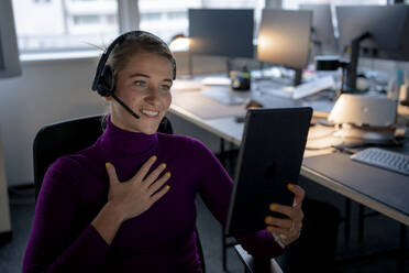 Lächelnder Kundendienstmitarbeiter, der bei einem Videoanruf über einen Tablet-PC gestikuliert und spricht - JOSEF23537
