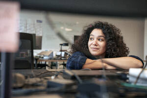 Smiling businesswoman leaning on desk in office - JOSEF23539