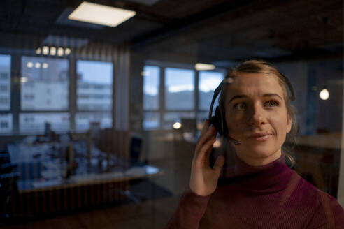 Saleswoman talking to customer through headset in office - JOSEF23547