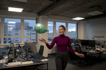 Glückliche junge Geschäftsfrau spielt mit Luftballon im Büro - JOSEF23552