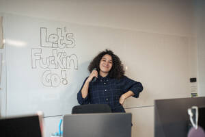 Smiling businesswoman standing near whiteboard in office - JOSEF23557