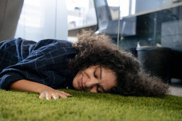 Lächelnde Geschäftsfrau, die sich auf einem Teppich im Büro ausruht - JOSEF23580