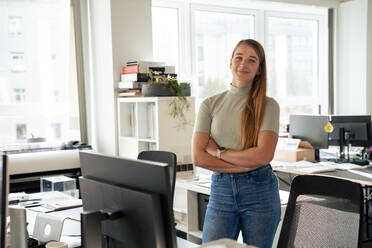 Young businesswoman standing with arms crossed in office - JOSEF23586