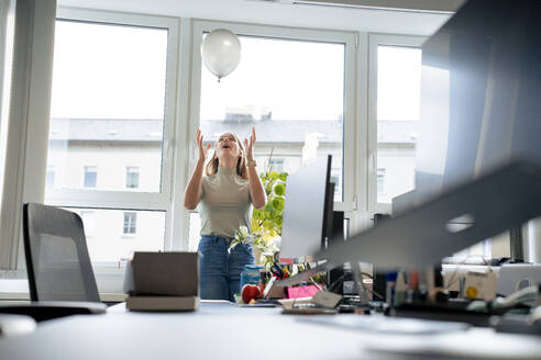 Unbekümmerte Geschäftsfrau spielt mit Luftballon im Büro - JOSEF23587