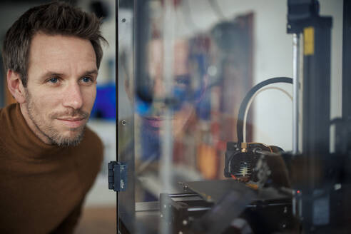 Ingenieur betrachtet 3d-Drucker in einer Glasvitrine in der Werkstatt - JOSEF23595