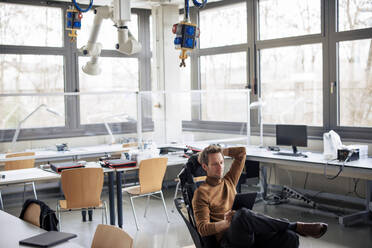 Ingenieur mit Tablet-PC auf einem Stuhl in der Werkstatt sitzend - JOSEF23622