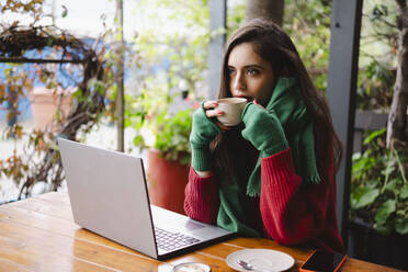 Geschäftsfrau trinkt Kaffee in der Nähe des Laptops in einem Cafe - AMWF02039