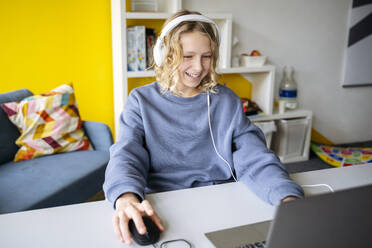 Happy boy playing video game on laptop at home - NJAF00804