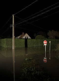 Frankreich, Hauts-de-France, Calais, Überschwemmte Straße bei Nacht - MKJF00051