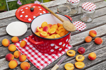 Zubereitung von Aprikosenmarmelade auf einem Holztisch im Garten - GWF07995