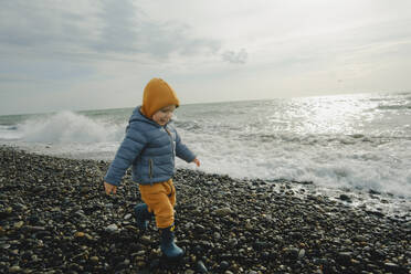 Lächelnder Junge beim Spaziergang am Kieselstrand - KVBF00020