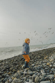 Boy having fun in front of birds at beach - KVBF00021