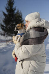 Frau stehend mit Hund im Winterpark - LESF00533