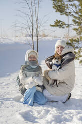 Lächelndes Mädchen mit Mutter und Hund im Winterpark - LESF00534
