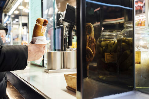 Junger Geschäftsmann kauft Hot Dog am Stand - AAZF01576