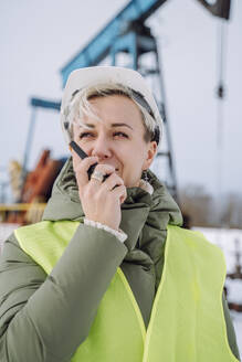 Ingenieur spricht mit Walkie-Talkie auf einem Ölförderfeld im Winter - OLRF00194