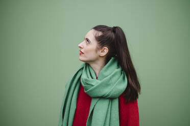 Woman wearing scarf and standing against green background - AMWF02042