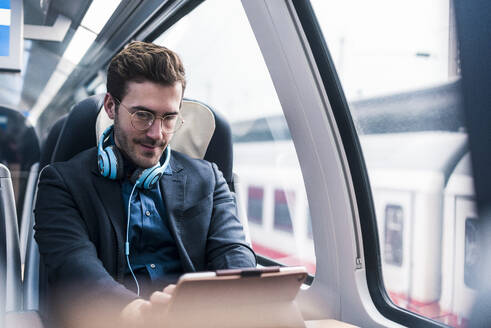 Businessman using tablet PC in train - UUF31449