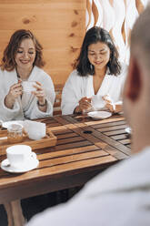 Smiling friends having tea at sauna - ADF00285