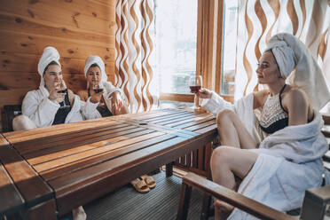 Junge Freunde genießen Wein am Tisch in der Sauna - ADF00287