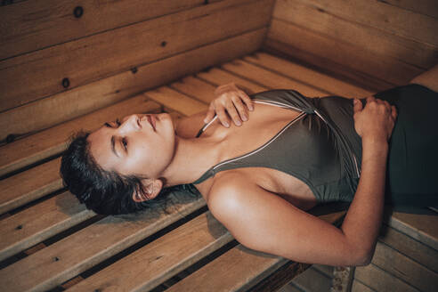 Junge Frau in der Sauna auf einer Bank liegend - ADF00291