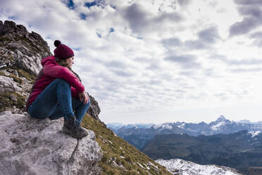 Young woman sitting on mountain at Bavarian Alps in Germany - UUF31455