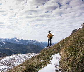 Hiker standing on mountain and looking at Bavarian Alps in Germany - UUF31459