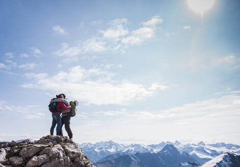 Paar, das sich auf dem Gipfel eines Berges in den bayerischen Alpen in Deutschland umarmt - UUF31466
