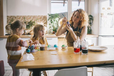 Woman coloring Easter egg with daughter sitting at home - ASHF00061