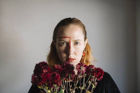 Ernste Frau mit rotem Lippenstift und Blumen vor grauem Hintergrund - ASHF00069