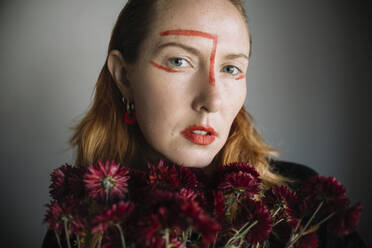 Woman with red lipstick marks on face against gray background - ASHF00072