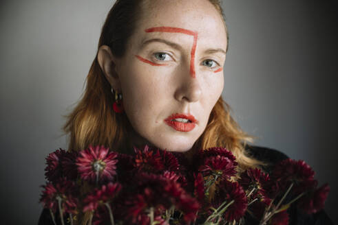 Frau mit roten Lippenstiftflecken im Gesicht vor grauem Hintergrund - ASHF00072