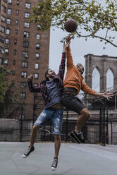 Happy friends slam dunking basketball at court - UUF31481