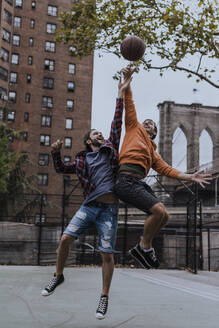 Glückliche Freunde beim Basketballspielen auf dem Platz - UUF31481