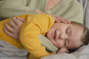Niedlicher Junge schläft im Arm seiner Großmutter zu Hause - KVBF00026