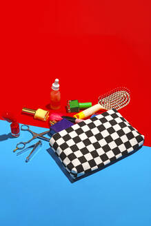 Studio shot of various cosmetics falling out of checked purse - RDTF00039