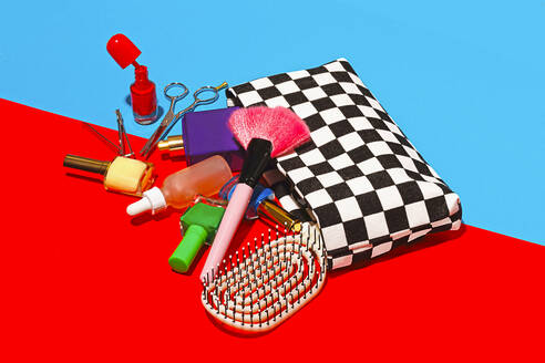 Studio shot of various cosmetics falling out of checked purse - RDTF00040