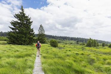 Mann mit Rucksack auf einer Wiese unter bewölktem Himmel - GWF08009