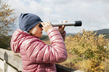 Mädchen mit Jacke und Blick durch ein Teleskop - ELMF00014