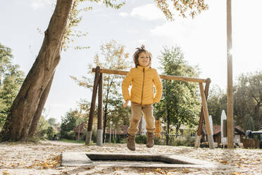 Kleiner Junge springt auf dem Spielplatz auf ein Trampolin - ELMF00019