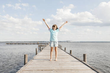 Happy girl standing on wooden pier at lake - ELMF00022