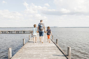 Father walking with sons on wooden pier at lake - ELMF00023