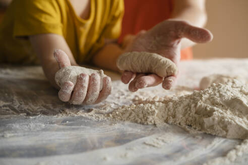 Grandson and grandmother holding dough buns in kitchen at home - KVBF00036