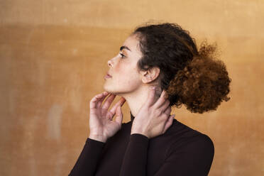 Junge Frau mit Haarknoten vor braunem Hintergrund - LMCF00948