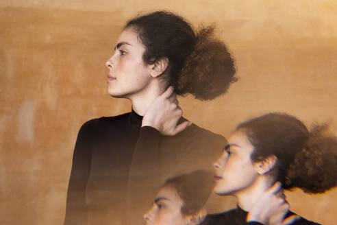 Multiple exposure of young woman with hair bun in front of wall - LMCF00949