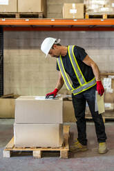 Worker examining checklist at wood distribution warehouse - DLTSF03783