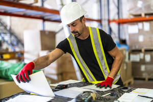 Worker examining documents at wood distribution warehouse - DLTSF03787