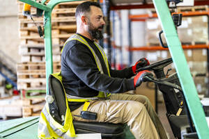 Mature worker driving forklift at warehouse - DLTSF03788