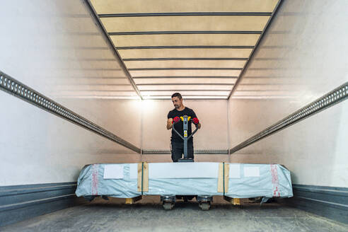 Worker pushing pallet jack loading in cargo container - DLTSF03805