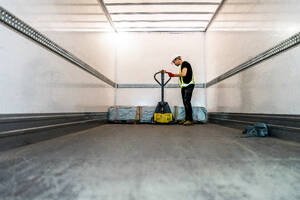 Worker with pallet jack loading in cargo container - DLTSF03806